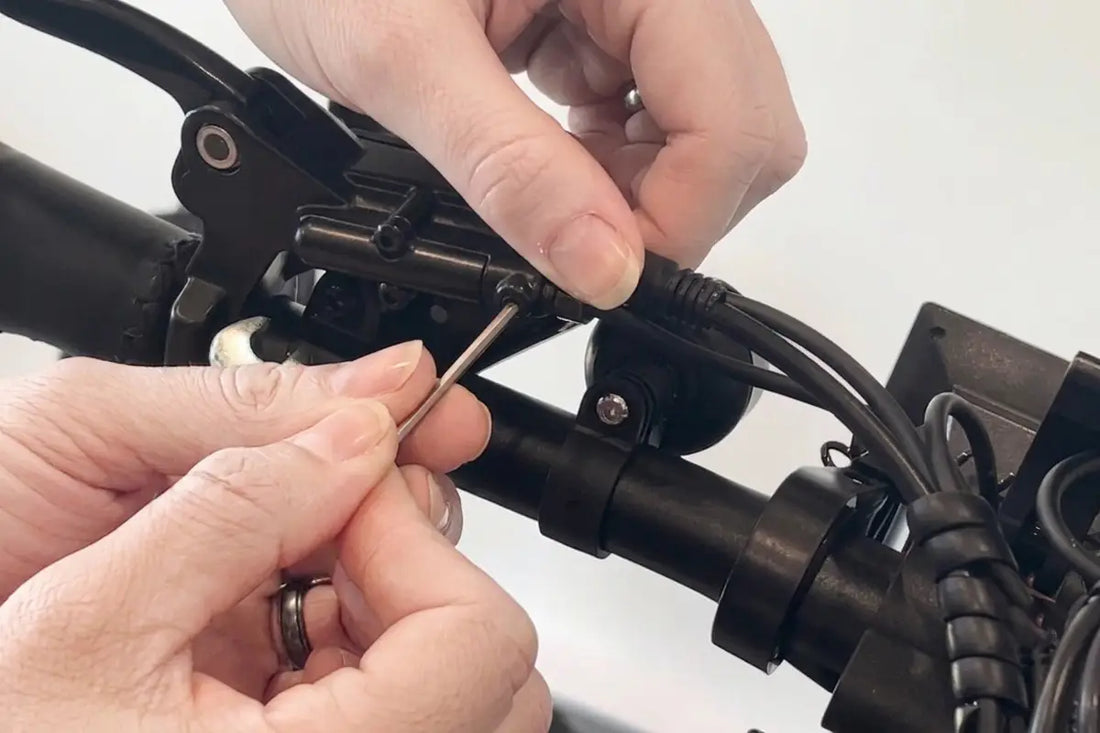 Close-up of a mechanic using a small hex key to adjust the complex black hydraulic brake lever and sensor wiring